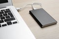 Charging modern laptop with power bank on table, closeup Royalty Free Stock Photo