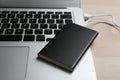 Charging modern laptop with power bank on table, closeup Royalty Free Stock Photo