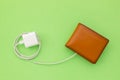 Charging the power to financial concept : Top view white charger cable connect to brown wallet on green Royalty Free Stock Photo