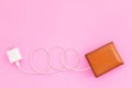 Charging the power to financial concept : Top view white charger cable connect to brown wallet on pink Royalty Free Stock Photo
