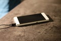 Charging white smart phone on graphite desk.