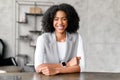 A charismatic African-American businesswoman greets with a warm smile from her desk Royalty Free Stock Photo