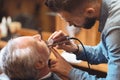 Charismatic barber shaping beard of the client in the barbershop