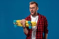 Charismatic cheerful young bearded man dressed in checkered shirt, white T-shirt and glasses, with yellow skateboard in