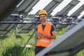 Charismatic with a cute smile young technician at solar power farm he holding his tablet to continue to work he standing Royalty Free Stock Photo