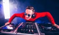 Charismatic DJ hovering over the turntable music control at night club