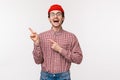 Charismatic funny young man in glasses and red beanie introduce something awesome, laughing and smiling excited pointing Royalty Free Stock Photo