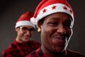 Charismatic male friends grinning at the camera in Santa Hats