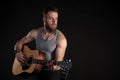 A charismatic man with a beard, playing an acoustic guitar, on a black isolated background. Horizontal frame Royalty Free Stock Photo