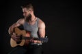 A charismatic man with a beard, playing an acoustic guitar, on a black isolated background. Horizontal frame Royalty Free Stock Photo