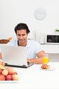 Charismatic man working on his laptop in kitchen