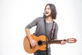 Charismatic positive young man singing in microphone and playing guitar Royalty Free Stock Photo