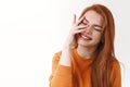 Charismatic pretty laughing redhead girl in orange sweater, close eyes and smiling joyfully, touching pure clean skin