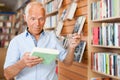 charismatic senior male customer visiting bookshop in search of interesting fiction