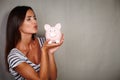 Charismatic young woman kissing a piggy bank