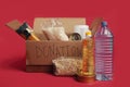 Charity concept. Open donation cardboard box with various food on a red background Royalty Free Stock Photo