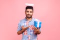 Charity and donations. Portrait of angelic bearded man with halo over head wearing blue shirt showing gift box and smiling at