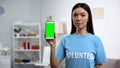 Charity fund worker showing smartphone green screen, volunteering app, help
