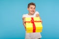 Charity and generosity. Kind happy man in white t-shirt giving gift box to camera and smiling