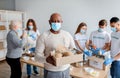 Charity organization. African american senior man holding box with donations food, wearing medical mask Royalty Free Stock Photo