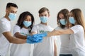 Charity organization concept. Group of multiracial volunteers in masks and gloves joining hands together
