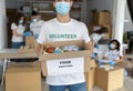 Charity organization. Male volunteer in medical mask, holding box with food donations, closeup, cropped