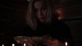 Charlatan witch reading book of black magic, view on burning candle. magic ritual