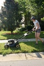 Charlotte, North Carolina-June: Young Woman is Mowing Lawn with headphones