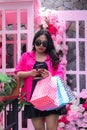 Women Asian beautiful in pink shirt happy cheating her friend hands carrying debit card, smartphone and paperbag in