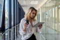 Charm young businesswoman holding digital tablet standing in corridor of a modern business center