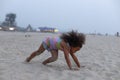 Charming African American girl is doing sports on summer day at beach. Outdoor activities.