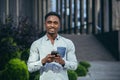 Charming african american man happy looking at camera, holding mobile phone in hands smiling and happy Royalty Free Stock Photo