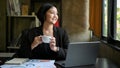 Charming Asian businesswoman enjoys her morning coffee at her desk Royalty Free Stock Photo