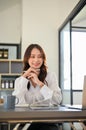 Charming Asian businesswoman sits at her office desk, looking at laptop screen Royalty Free Stock Photo