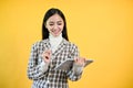 A charming Asian businesswoman stands against an isolated yellow background with her tablet Royalty Free Stock Photo