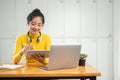 A charming Asian female university student using her digital tablet while sitting in a library Royalty Free Stock Photo