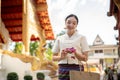 Charming Asian lady in a traditional Thai-Northern dress is visiting a temple on a Buddhist holy day