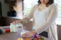 Charming Asian pregnant woman is holding bottle of milk and pouring milk to a glass. Attractive woman need protein and calcium for Royalty Free Stock Photo