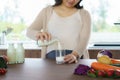 Charming Asian pregnant woman is holding bottle of milk and pouring milk to a glass. Attractive woman need protein and calcium for Royalty Free Stock Photo