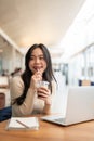 A charming Asian woman enjoying her iced coffee while working remotely at a coffee shop Royalty Free Stock Photo