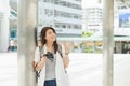 Charming Asian woman in gray shirt and open shirt carrying a backpack and holding camera, make a finger point on the air  from Royalty Free Stock Photo