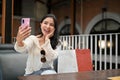 Charming Asian woman with her shopping bags, using her smartphone to take a selfie Royalty Free Stock Photo