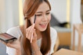 Attractive young Asian female beauty influencer applying makeup, using an eye shadow Royalty Free Stock Photo