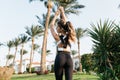 Charming attractive young woman stretching hands above in sunny morning in tropical city. View from back, outwork Royalty Free Stock Photo