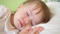 Charming baby falls asleep on white bed in his bed in room at home. concept of sleeping child. child wants to sleep and Royalty Free Stock Photo