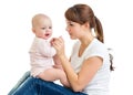 Charming baby girl looking away and smiling while sitting on his mother`s knees. Mom is looking at her child Royalty Free Stock Photo