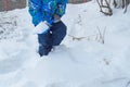 Charming baby little boy digging snow blue small shovel in winter day Royalty Free Stock Photo