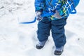 Charming baby little boy digging snow blue small shovel in winter day Royalty Free Stock Photo