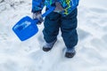 Charming baby little boy digging snow blue small shovel in winter day Royalty Free Stock Photo