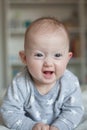 Portrait of a charming baby lying on its stomach and laughing. Family morning at home. Tummy time